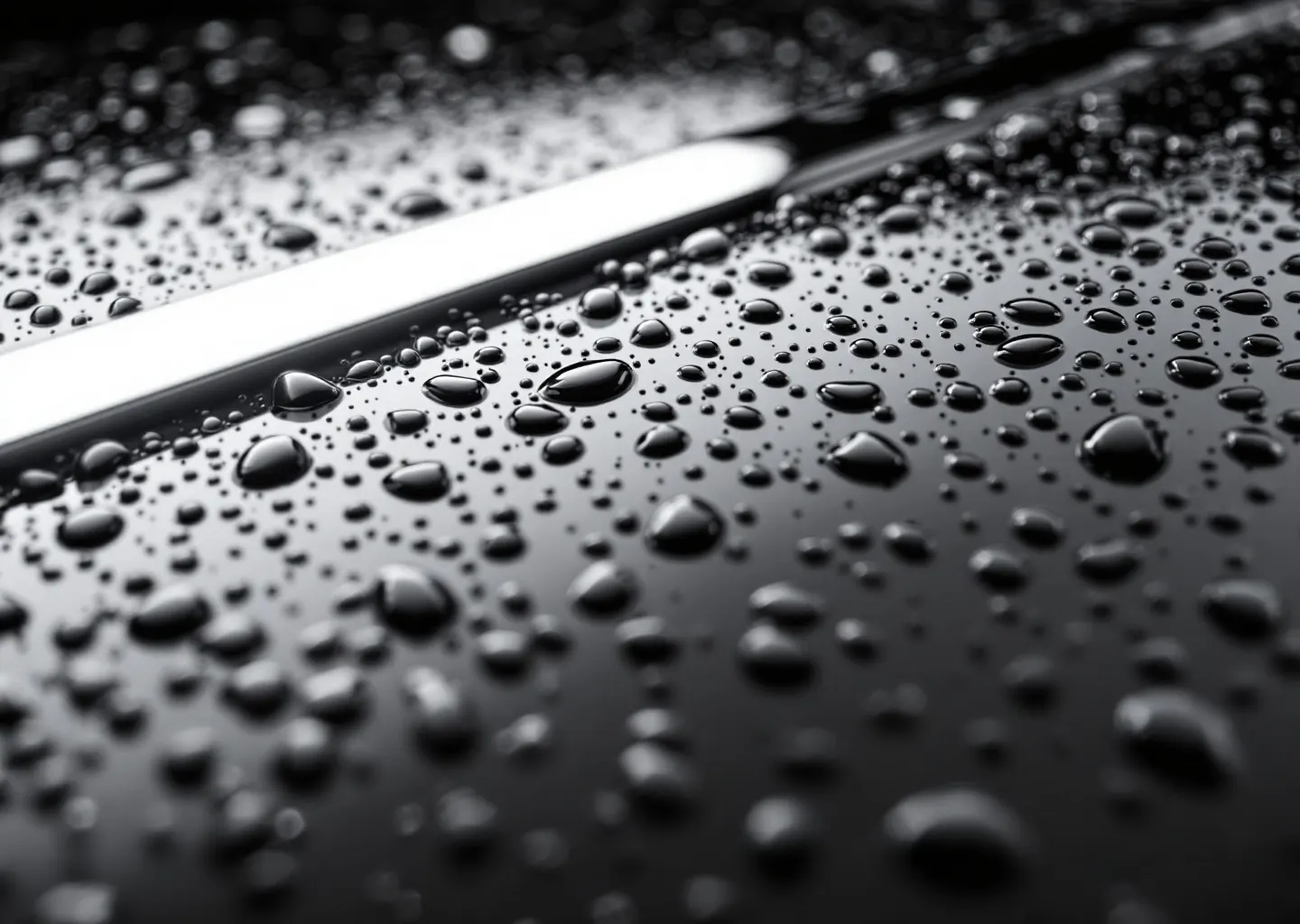 Water beads standing on coated mirror-black paint, each carrying an arc of the LED bar