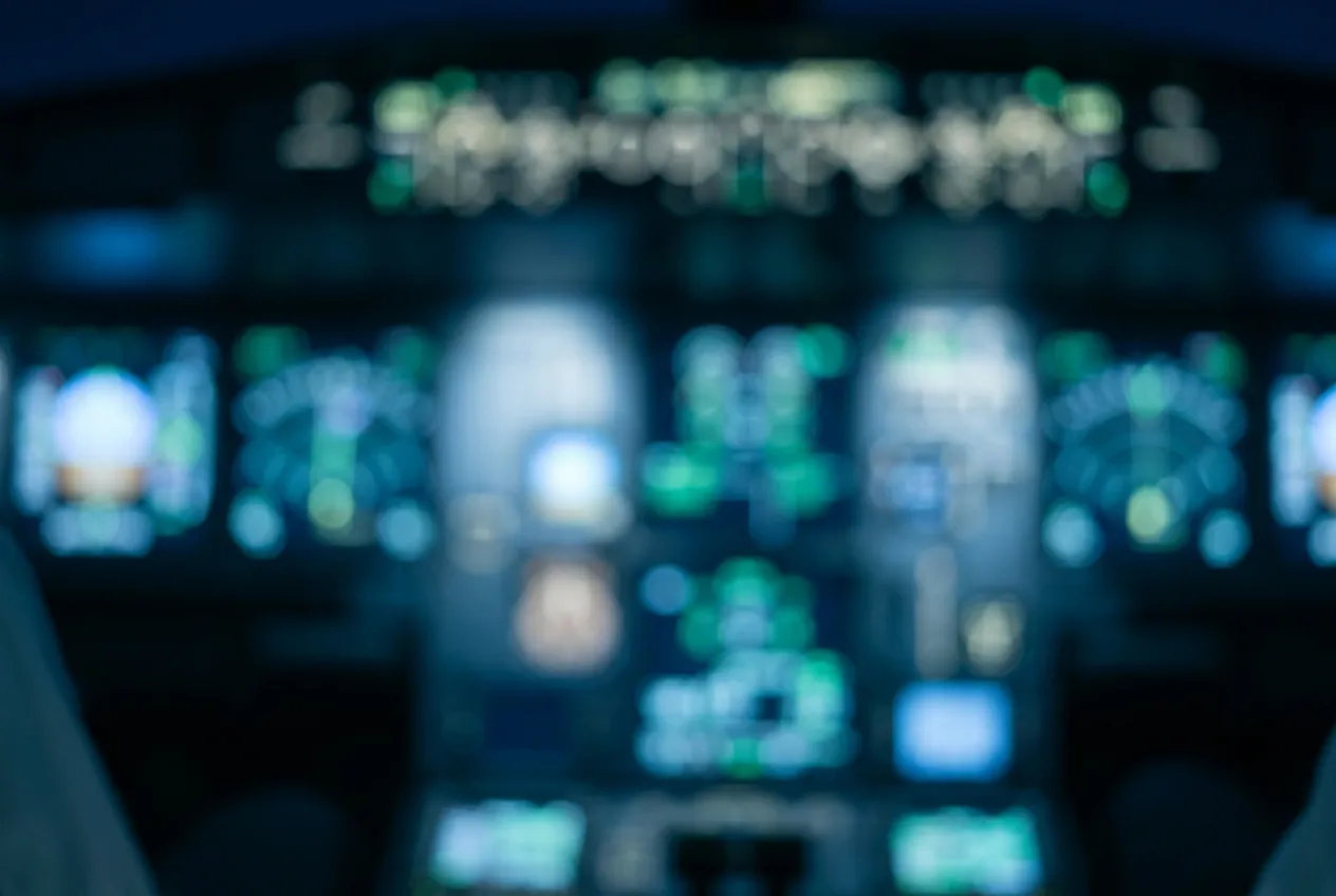 Defocused glass cockpit instruments glowing in a dark flight deck