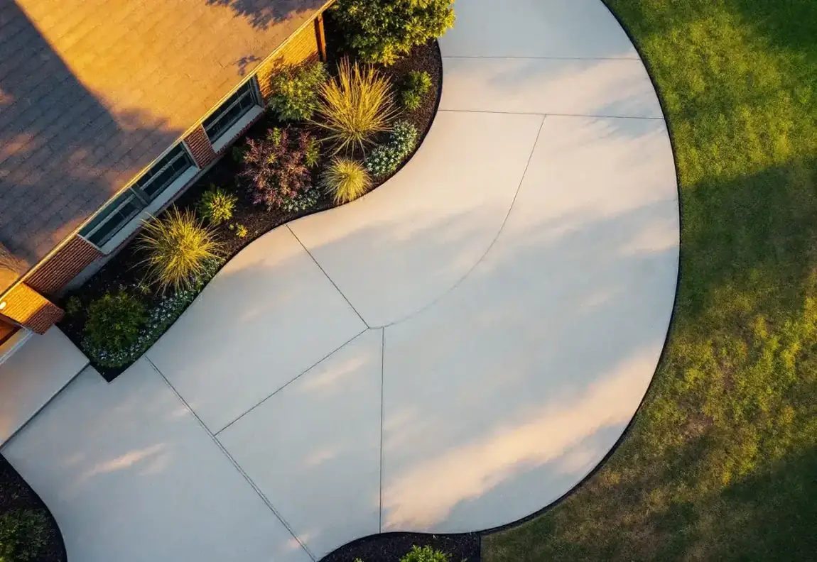 Drone view of a new Monolith & Form driveway at dawn, saw-cut joints casting long shadows