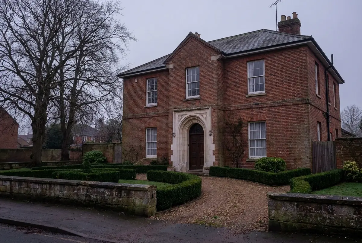 The red-brick Merriden House behind its clipped hedges on an overcast morning