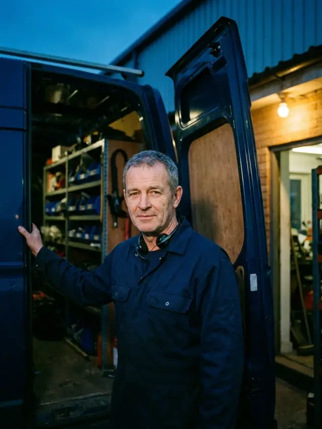 Ray Fairbanks, owner and dispatch lead, at the open rear door of his service van at night