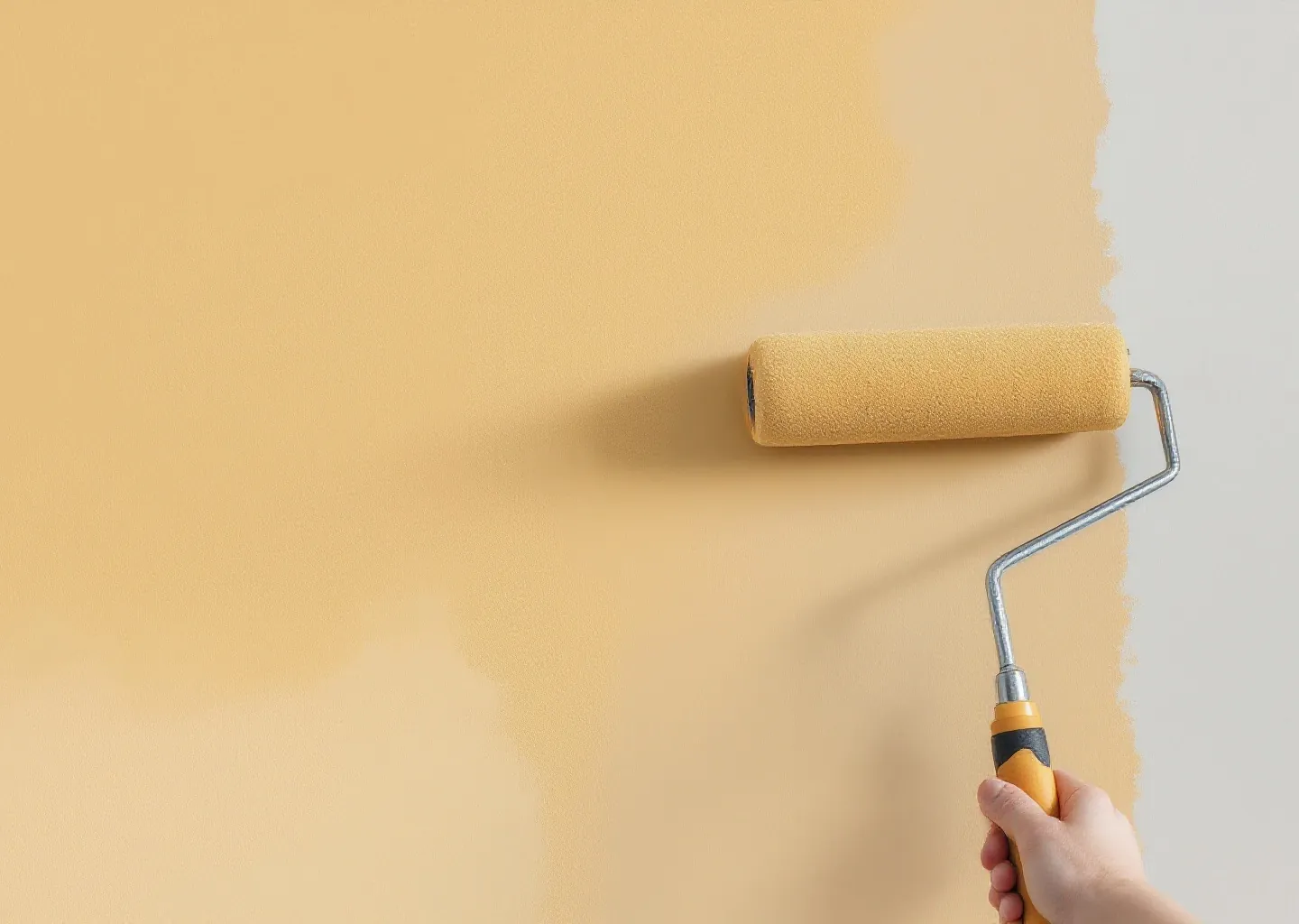 Roller frozen mid-stroke laying marigold across a primed wall