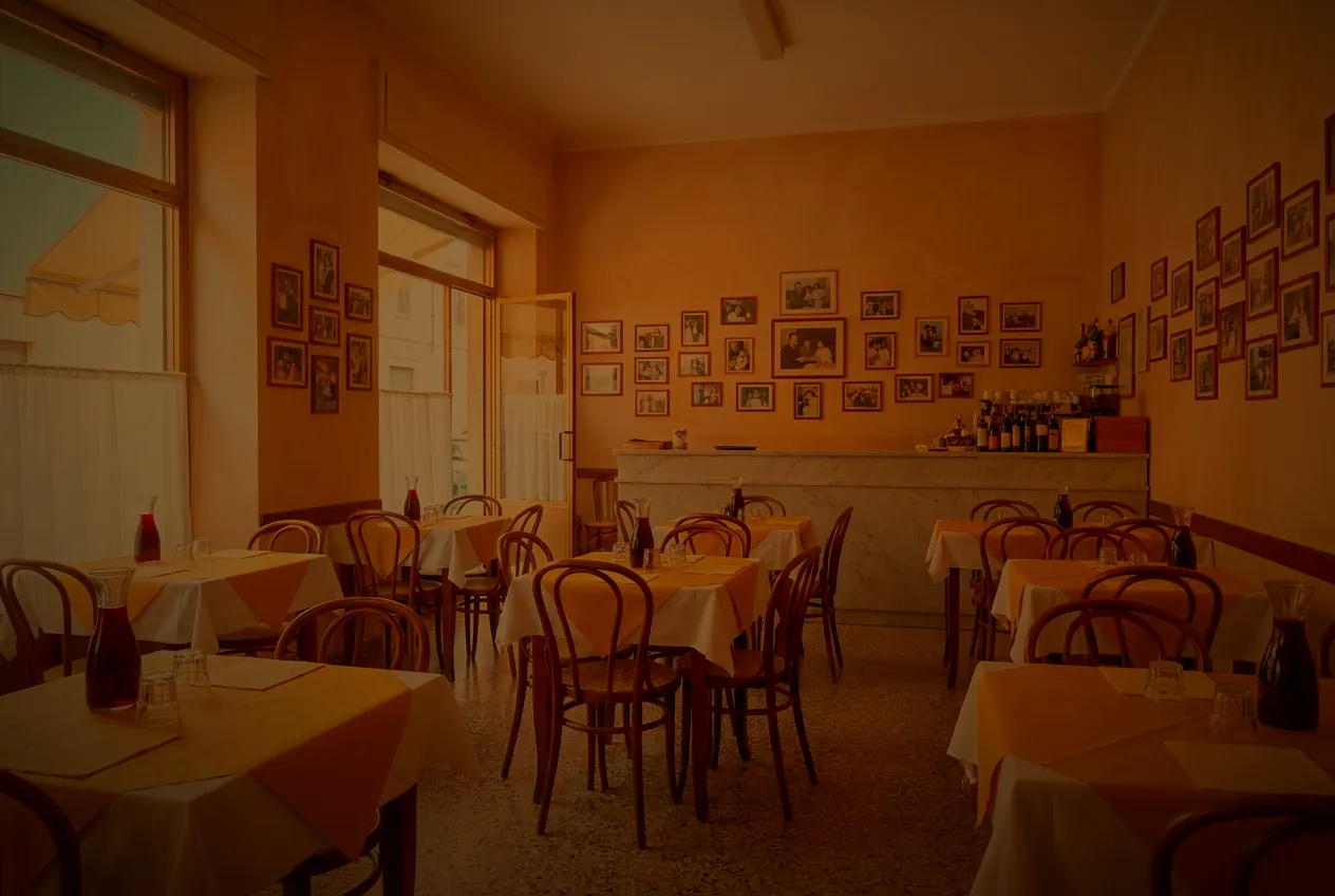 The trattoria dining room, straw paper laid on every table, carafes of red wine waiting.